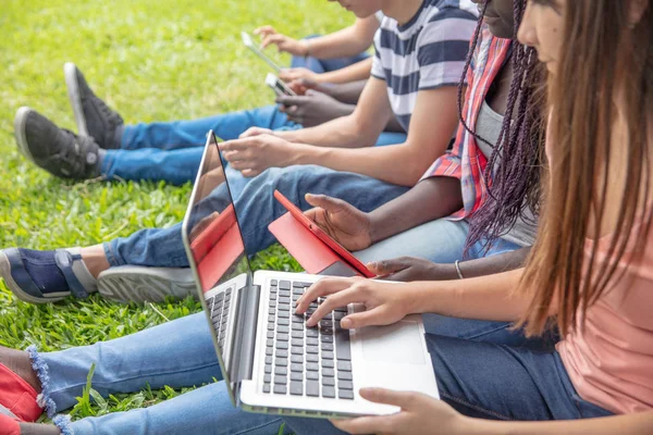 一群混种族青少年使用笔记本电脑和智能手机户外 — 图库照片
