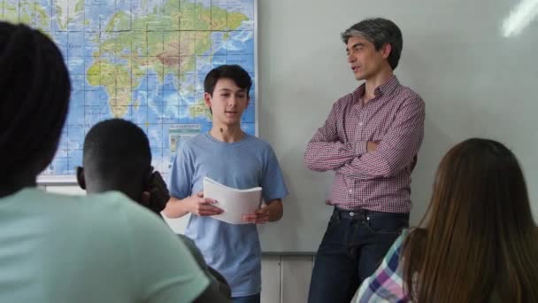 先生と肯定的な多民族青少年教室生徒にレッスンを説明する 代の少年 — ストック動画