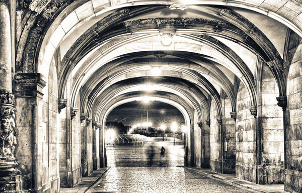 Shadows of people walking at night under ancient medieval loggias.
