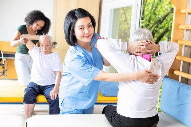 Asya ve Afrika hemşireler rehabilitasyon tesis spor salonunda yaşlı çift yardım.