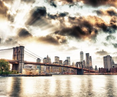 Manhattan siluetinin ve gün batımında, New York'un Brooklyn Bridge Park Brooklyn Köprüsü'nün görünümünden.