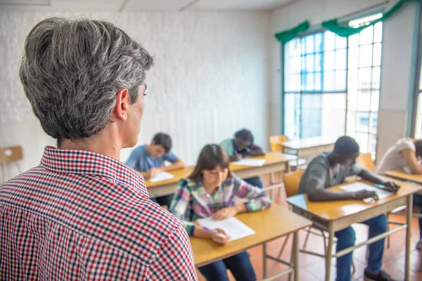 Öğretmen okul testleri bir genç sınıf öğrencileri kontrol.