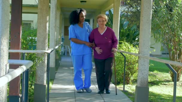 Медсестра Допомагає Літнім Пацієнткам Ходити Парку — стокове відео