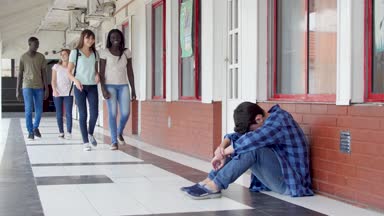 okul koridorda yürüyüş ve katta oturan bir çocuk zorbalık genç grup 