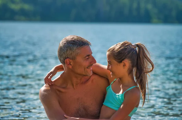 湖に沿って休暇中の父と娘は愛をもってお互いを見ている 休暇のコンセプト — ストック写真