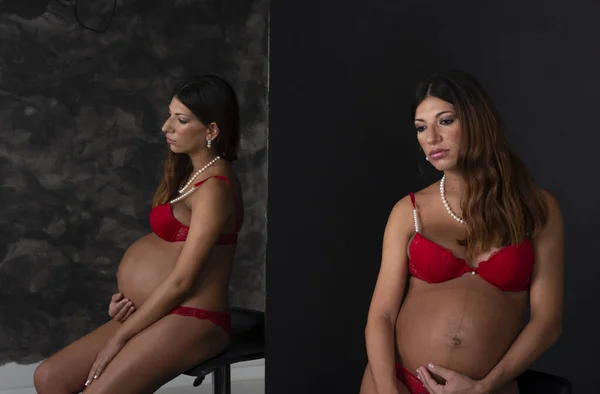 Concepto Embarazo Mujer Morena Vestida Rojo Sentada Una Silla Sosteniendo —  Fotos de Stock