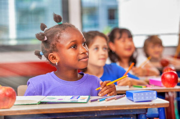 Multi ethnic elementary classroom looking at the teacher.