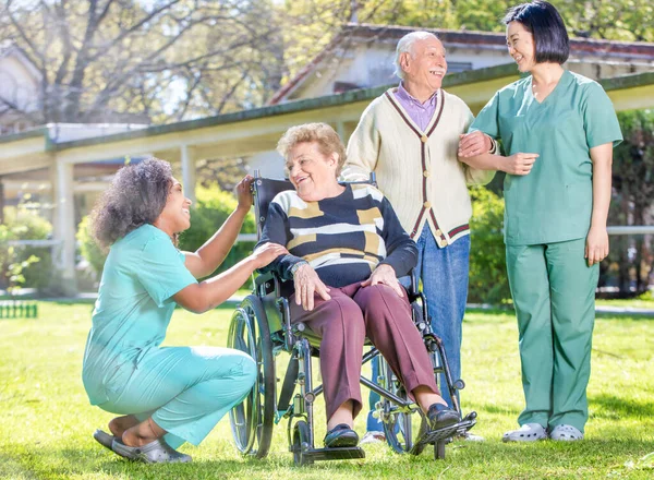 Female Doctor Reassuring Elderly Retired People Hospital Garden — Stock Photo, Image