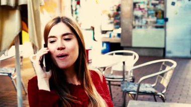 Restoranda telefonla konuşan genç ve güzel bir kadının görüntüleri.