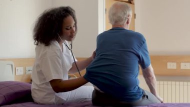 Huzurevinde yaşlı bir adamla ilgilenen hemşirenin görüntüleri.