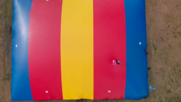 カラフルなトランポリンで飛び回る子供の空中映像 — ストック動画