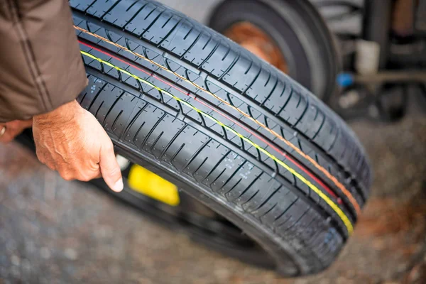 Un joven cambiando el neumático pinchado de su coche —  Fotos de Stock