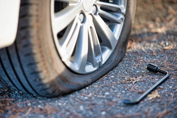 Pneu plat sur la route avec clé à molette le long — Photo