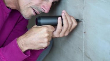 Elinde elektrikli tornavida olan yakışıklı bir adamın görüntüleri.