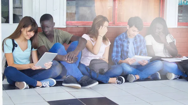 Πολυεθνικοί Συμμαθητές Που Κάθονται Στο Διάδρομο Του Σχολείου Χαλαρώνοντας Και — Φωτογραφία Αρχείου