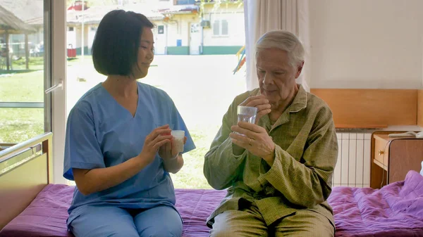 Jovem Asiático Médico Feminino Ajudando Idosos Aposentado Homem Tomando Pílula — Fotografia de Stock