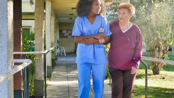 病院の庭で高齢者の女性と話すアフリカの女性医師 幸福と退職の概念 — ストック写真