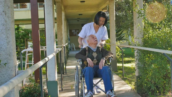 Asian Female Doctor Talking Elderly Retired Man Wheelchair Hospital Yard — Stock Photo, Image