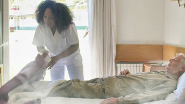 Genç Afrikalı kadın doktor yaşlı bir adamın hastaneye yatmasına yardım ediyor..