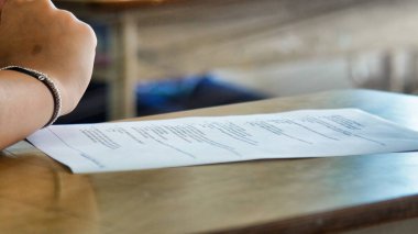 Okuldaki masanın üstünde kağıt parçasıyla genç bir el.