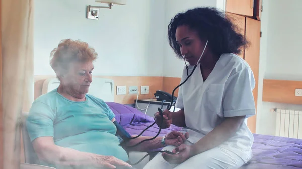 在医院病床上看老年女病人的非洲女医生 康复和退休概念 — 图库照片