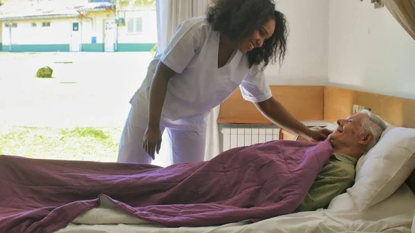 Joven Médico Africano Ayudando Ancianos Jubilados Cama Hospital —  Fotos de Stock