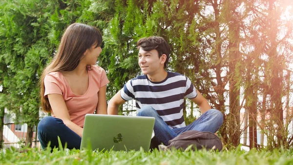 使用笔记本电脑躺在草地上的多种族青少年夫妇 幸福与光明的概念 — 图库照片