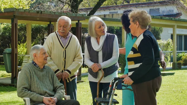 アフリカの看護師は リハビリ病院の庭の屋外で2人の高齢者の退職したカップルと話します 幸福とリハビリテーションと退職の概念 — ストック写真