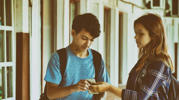 在学校走廊里 一对白人青少年夫妇在看智能手机 — 图库照片
