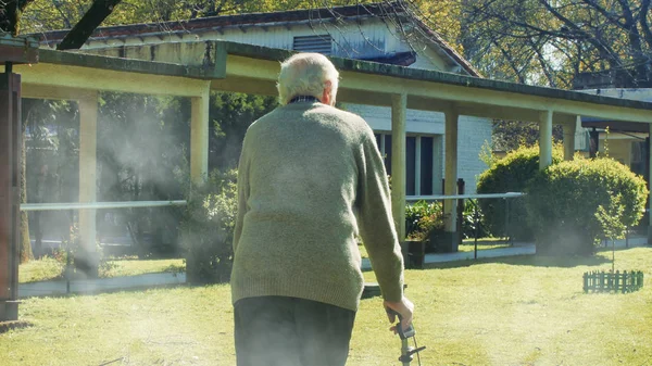 Hombre mayor jubilado con paseantes paseando por el jardín. — Foto de Stock