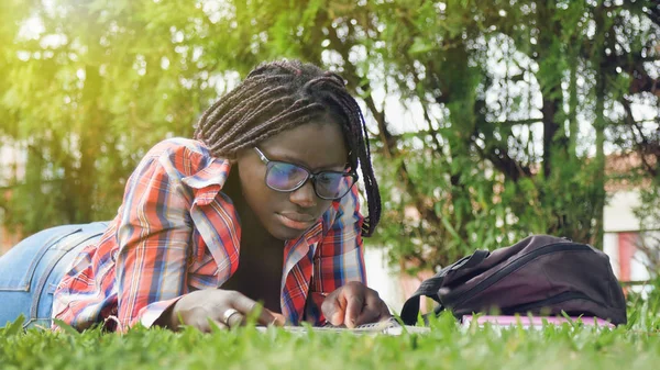 アフリカ系の10代の少女が芝生の上で学校の授業をしている 幸福と軽さの概念 — ストック写真