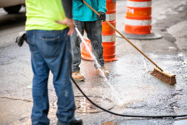 Wegwerkers die de straat schoonmaken met water — Stockfoto