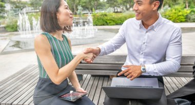 Genç Asyalı girişimcilerin iş toplantısı. Bir dizüstü bilgisayarın önünde el sıkışma anlaşması..