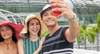 Şehirde yürüyen ve selfie çeken üç melez cinsiyet arkadaşı. Turizm ve tatil konsepti.