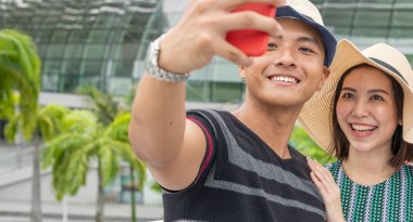 Genç Asyalı çift selfie çekerek şehirde yürüyor. Touris
