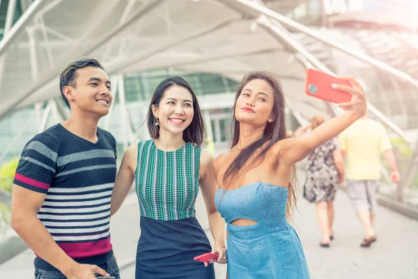 Três amigos asiáticos andando ao longo da cidade tomando selfies. Touri — Fotografia de Stock