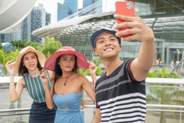 Şehirde yürüyen ve selfie çeken üç melez cinsiyet arkadaşı. Turizm ve tatil konsepti.