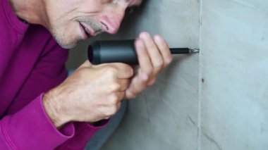 Elinde elektrikli tornavida olan yakışıklı bir adamın görüntüleri.