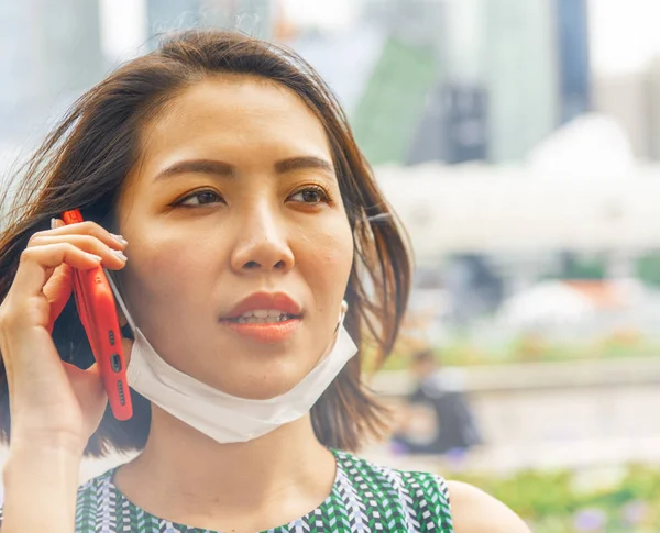 Jeune femme asiatique avec téléphone portable et masque anti-pollution — Photo