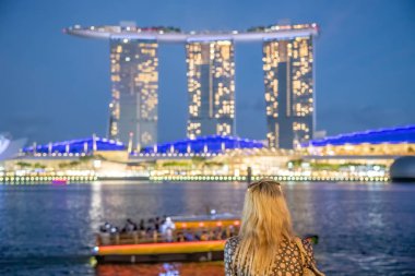 Günbatımında Singapur siluetini izleyen güzel bir kadın.