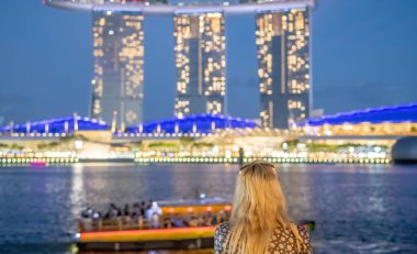 Günbatımında Singapur siluetini izleyen güzel bir kadın.