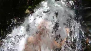 Şelalenin altında duran yetişkin bir adamın görüntüleri.