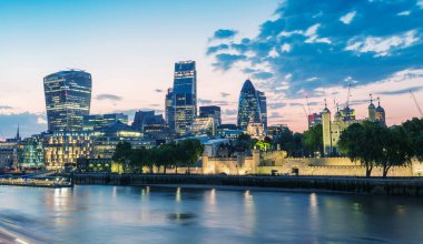 Alacakaranlıkta harika bir Londra silueti. Thames nehrindeki binalar ve yansımalar.