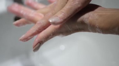 Kadın ellerini su ve sabunla iyice yıkıyor. Coronavirus önleme tedbirleri.