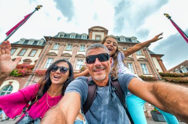 Şehir ziyareti sırasında mutlu aile şakaları ve gülümsemeleri. Mutluluk, tatil ve seyahat konsepti. Anne baba ve kızı selfie çekiyor.