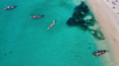 Tayland 'daki tropik bir sahil boyunca uzun kuyruklu teknelerin havadan görüntüsü..