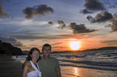 Mutlu genç çift kumsalda güzel günbatımının tadını çıkar.