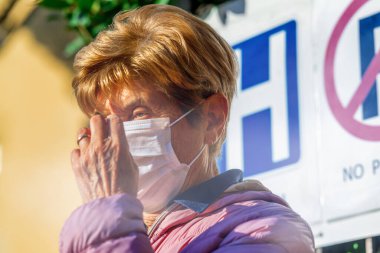 Hastanenin önündeki yaşlı kadın, Coronavirus için endişelenen sağlık maskesi takıyor..