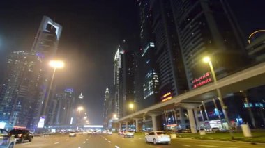 DUBAI, BAE - 2016 ARALIK: Gece hareket halindeki bir araçtan şehir merkezi binaları. Şehir yılda 30 milyon turist çekiyor..