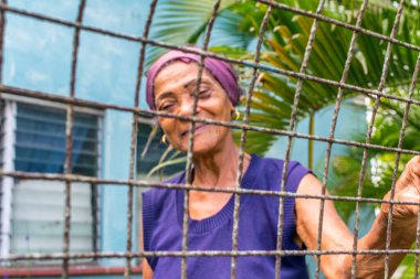 HAVANA, CUBA - 4 Nisan 2016: Metalik bir çitin arkasındaki yaşlı Kübalı kadının portresi, Orta Havana, Centro Habana, Küba.